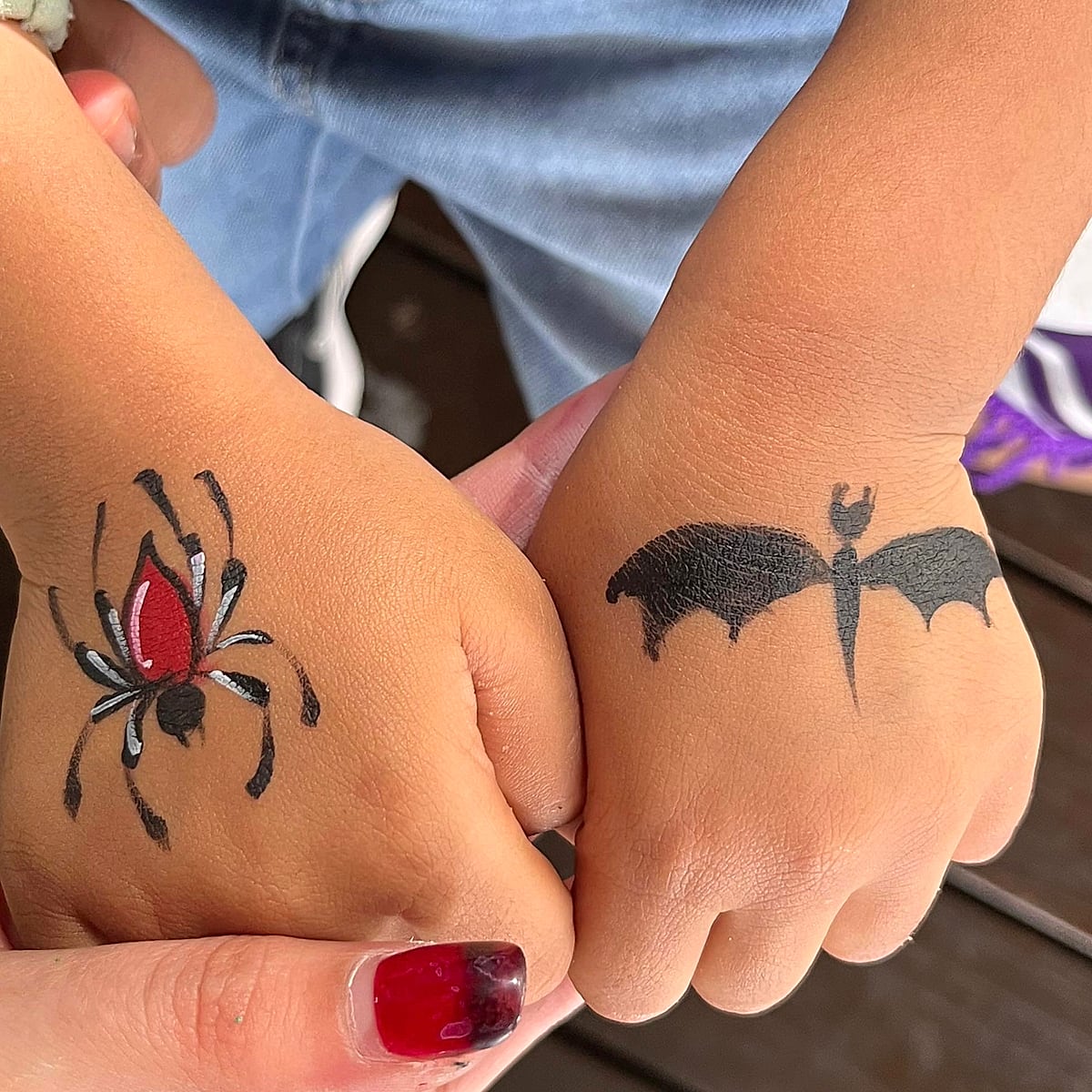 Two small fists, one painted with a red and black spider, the other with a black bat