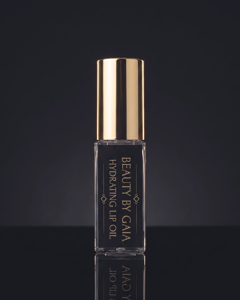 Beauty by Gaia Hydrating Lip Oil, a clear glass bottle with a black and gold label and a tall gold cap