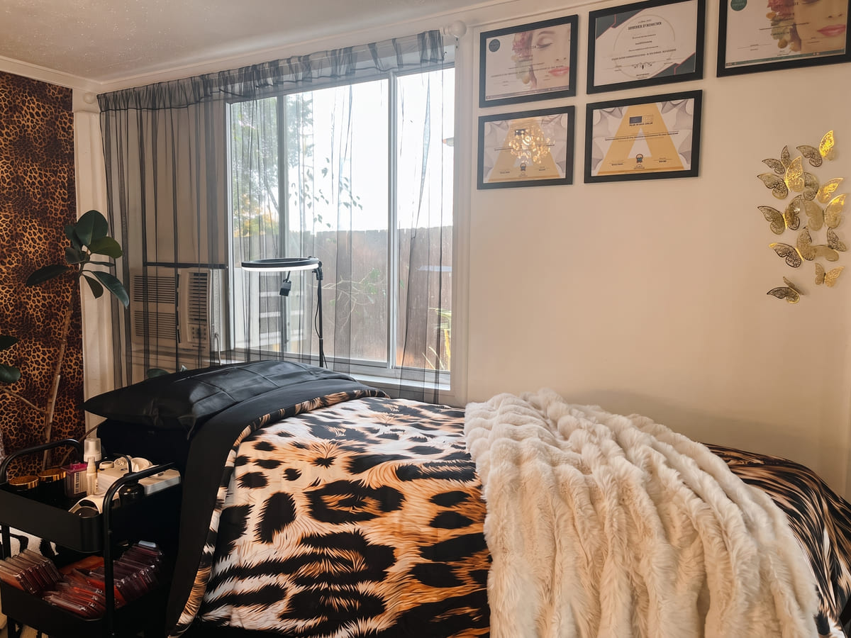 The treatment bed at Beauty by Gaia, made up in leopard print, below five framed lash and brow qualifications