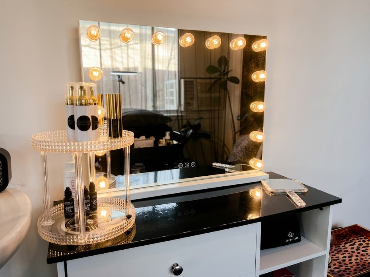 The lit vanity mirror at Beauty by Gaia, with the lash care products on the shelf